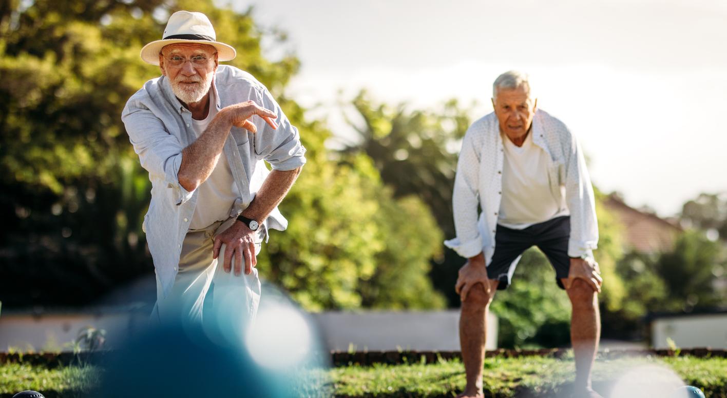 Two residents playing lawn bowls on a sunny afternoon